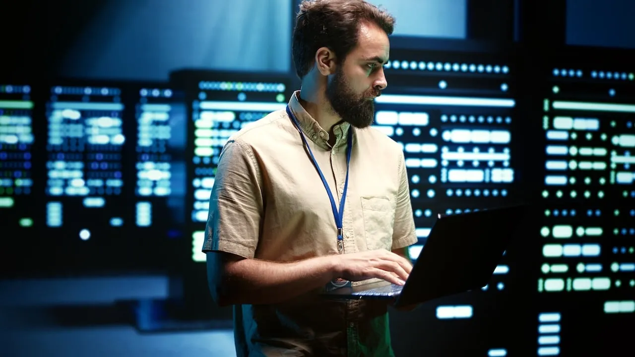 A business professional in a blue shirt smiling and engaging in a discussion with a colleague, while seated at a modern office table. The laptop in front of them displays graphs and data visualizations, representing a business strategy or analysis. The scene portrays a collaborative environment focused on innovation and growth, emphasizing the importance of modernizing legacy systems to enhance performance and efficiency in business.